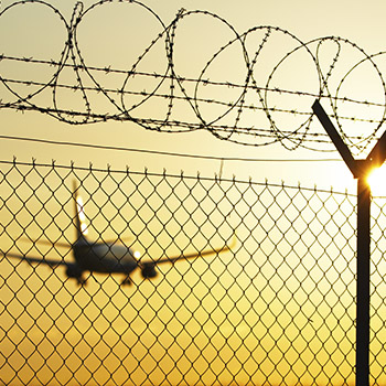 Airplane taking off in the distance with barbed wire fence in the foreground